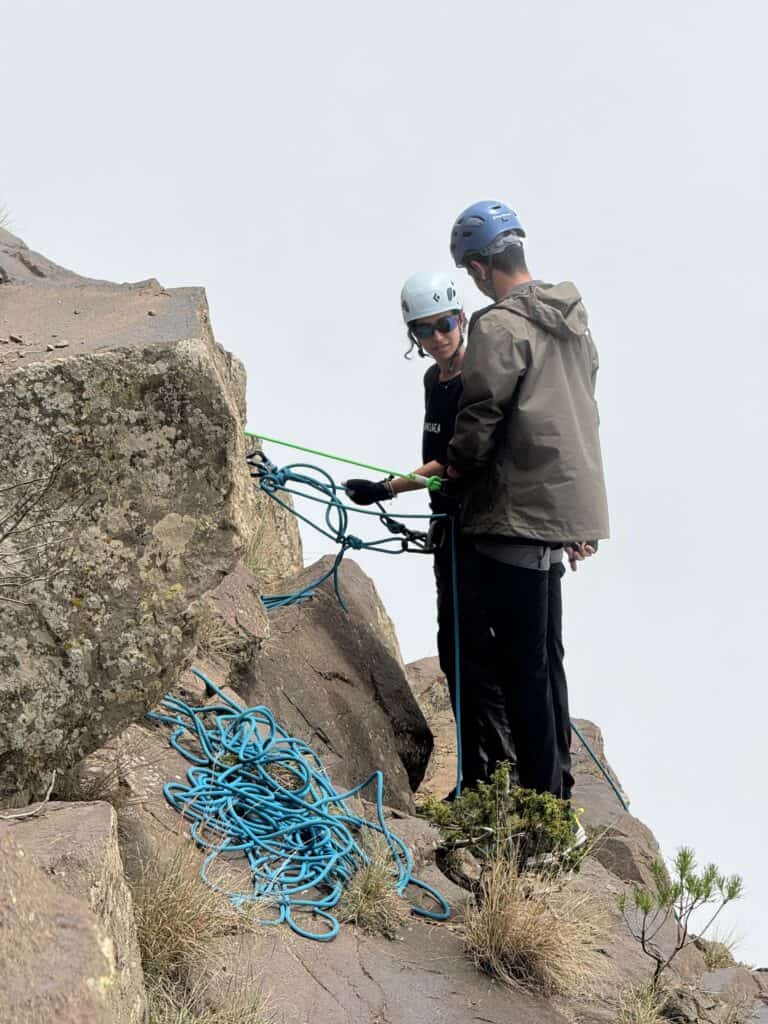 Climbers securing ropes on a mountain cliff for safety and ascent.