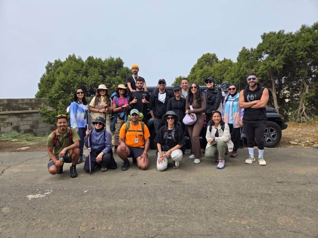 Group of diverse hikers outdoors near trees and a car on a clear day.