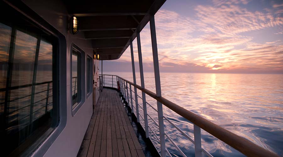 Expedition ship sailing at sunset in polar waters